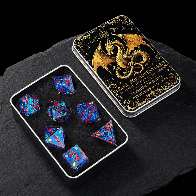 May include: A set of seven polyhedral dice with blue and red stained-glass patterns and red numbers, housed in a black foam-lined metal tin. The tin lid features a gold dragon illustration and the text ROLL FOR ADVENTURE PREMIUM DND DICE.