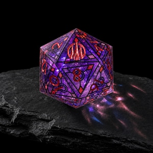 May include: A twenty-sided die featuring a translucent purple and blue galaxy-like interior with intricate black geometric linework and metallic red numbering. The die displays a prominent red symbol on the top face and clear numerical digits.