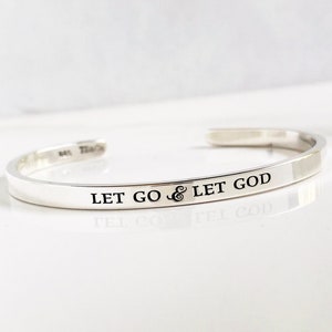 May include: Silver bangle bracelet with the inscription "Let go & let God".