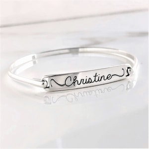 May include: Silver bangle bracelet with a personalized nameplate that reads "Christine" in a cursive font.