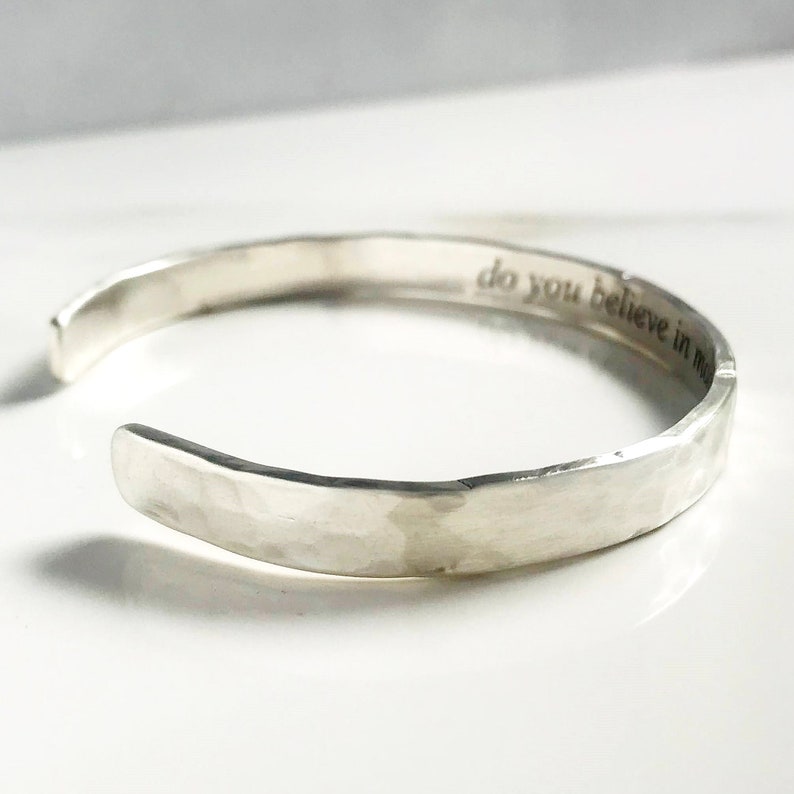 Puede incluir: Un brazalete de plata martillado con la inscripci&oacute;n "do you believe in magic" en el interior.