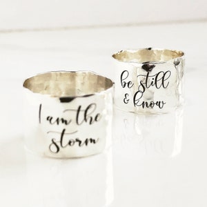 May include: Two silver rings with hammered textures. One ring says "I am the storm" and the other says "be still & know".