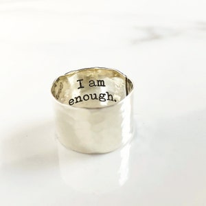 May include: A silver hammered ring with the words "I am enough." engraved on the inside.
