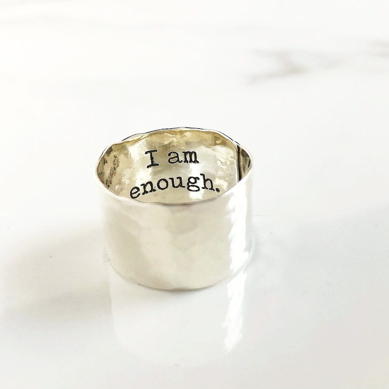May include: A silver hammered ring with the words "I am enough." engraved on the inside.