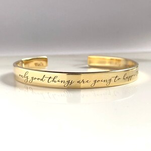 May include: Gold bangle bracelet with the inscription "only good things are going to happen to you".