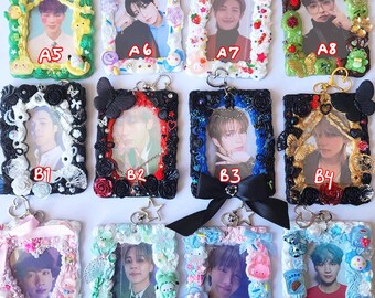 May include: A collection of sixteen decorative photo frames, each with a unique design and a photograph. Frames feature various embellishments like flowers, bows, and charms in a variety of colors. Each frame has a keychain attached.