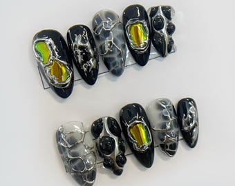 Uñas postizas futuristas iridiscentes, color negro y plateado, con pegamento cromado 3D, estilo cyberpunk.