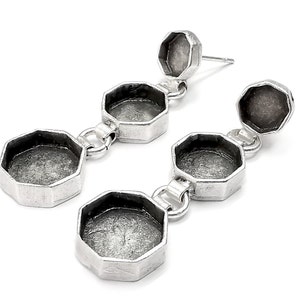 May include: Silver tone earrings with three octagonal shaped pendants. Each pendant has a smooth, round, open space in the center.