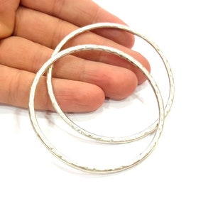 May include: Two silver hoop earrings with a hammered texture.