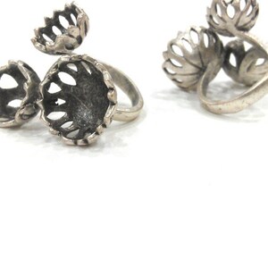 Puede incluir: Dos anillos de plata con un diseño floral. Los anillos están hechos de metal calado intrincado y tienen un aspecto delicado y femenino.