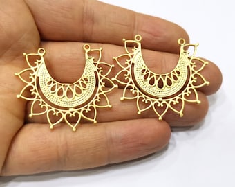 May include: Two gold-toned metal earring blanks with a filigree design. The blanks are shaped like a crescent moon with a decorative border.