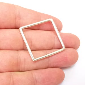 May include: A silver square ring with a smooth, polished finish.