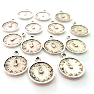 Könnte beinhalten: Eine Gruppe silberfarbener Uhren-Anhänger mit römischen Ziffern und einem herzförmigen Design in der Mitte jedes Zifferblatts.