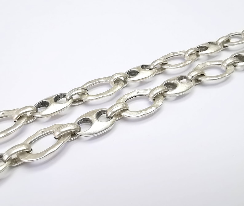 May include: A silver chain necklace with oval links. The links have a textured, hammered finish.