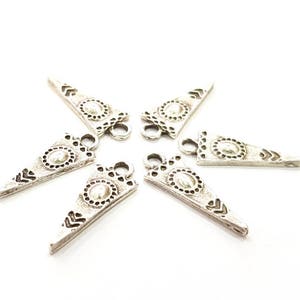 Puede incluir: Seis abalorios de plata en forma de triángulo con un diseño decorativo y un bucle en la parte superior.