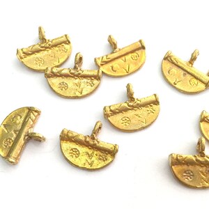 May include: Eight gold-toned metal charms with a scroll design and a half-circle shape. The charms have a loop at the top for attaching to a necklace or bracelet.