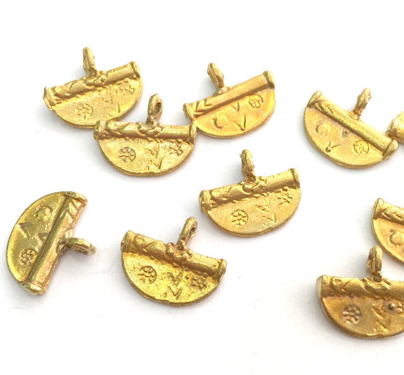 May include: Eight gold-toned metal charms with a scroll design and a half-circle shape. The charms have a loop at the top for attaching to a necklace or bracelet.