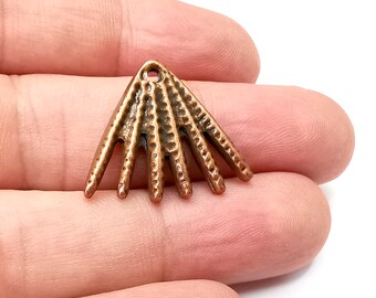 May include: A copper-colored metal charm in the shape of a stylized sunburst with a hole at the top for hanging.