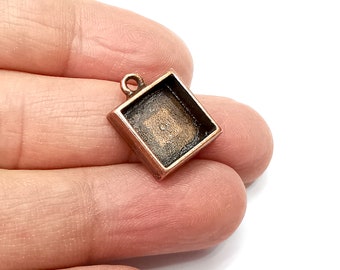 May include: A square copper pendant with a small loop at the top for attaching a chain. The pendant has a smooth, slightly textured surface and a raised edge around the perimeter.