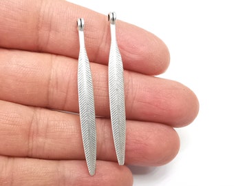 May include: Two silver feather-shaped charms with a textured surface. The charms are about 2 inches long.