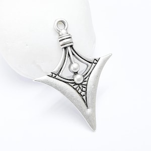 May include: Silver pendant with a geometric design and three round beads. The pendant is shaped like a triangle with a pointed tip.