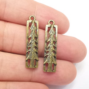 K&ouml;nnte beinhalten: Zwei antike goldfarbene Metall-Anh&auml;nger in Form von Tannenb&auml;umen. Jeder Anh&auml;nger hat oben eine &Ouml;se zum Anbringen an einer Halskette, einem Armband oder anderem Schmuck.