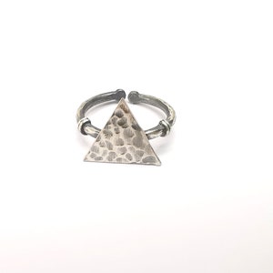 May include: A silver-toned ring with a hammered triangle design. The adjustable ring has a textured band and a geometric, open-ended design. The triangle is the focal point, adding a modern touch to the jewelry.