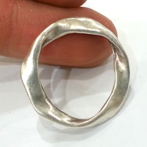 May include: A silver ring with a twisted, organic shape. The ring is smooth and polished, with a slightly textured surface.