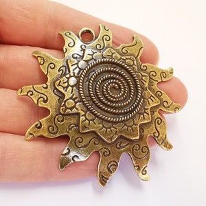 K&ouml;nnte beinhalten: Goldfarbener Metall-Sonnenanh&auml;nger mit einem Spiraldesign in der Mitte und filigranen Details an den R&auml;ndern.