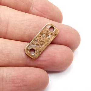 May include: A rectangular copper-coloured metal connector with two holes. The connector has a hammered texture.