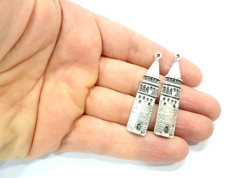 Puede incluir: Dos colgantes de plata con forma de la Torre de Galata en Estambul, Turqu&iacute;a. Los colgantes tienen un dise&ntilde;o detallado y son perfectos para la elaboraci&oacute;n de joyas.