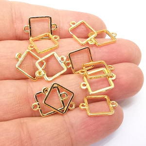 May include: A group of ten gold-toned metal square-shaped connector charms with two loops on each charm. The charms are designed to be used in jewelry making.