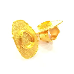May include: Two gold-colored metal rings with intricate floral designs. The rings are stacked on top of each other.
