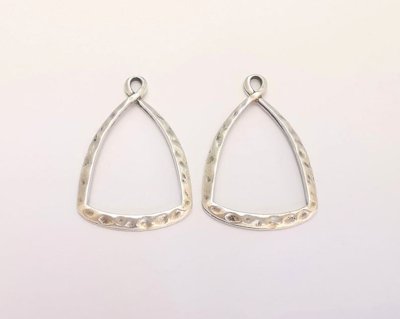 Puede incluir: Dos blanks de pendientes de plata en forma de tri&aacute;ngulo con textura martillada. Los blanks tienen un bucle en la parte superior para sujetar los hilos de los pendientes.