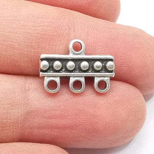 May include: Silver-toned metal connector with a row of small beads and four loops. This connector is used for jewelry making.