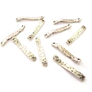 May include: A collection of silver-toned metal bar connectors with a hammered texture. The connectors have two holes on each end for attaching jewellery or other crafts.