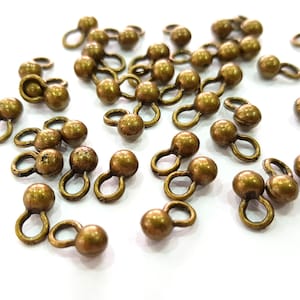 Peut inclure: Un groupe de fermoirs à bascule en métal doré antique avec une boule ronde à chaque extrémité. Les fermoirs sont éparpillés sur une surface blanche.