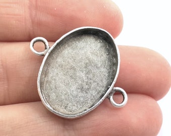 May include: Silver oval pendant setting with two jump rings. The setting is designed to hold a cabochon stone.