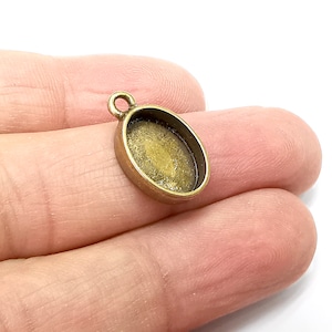 May include: A bronze oval pendant with a loop at the top for attaching a chain. The pendant has a smooth, slightly textured surface.