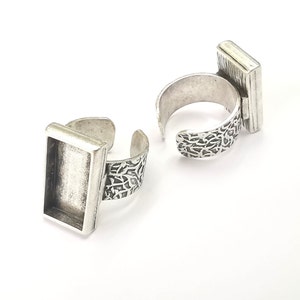 May include: Two silver rings with a rectangular bezel setting. The rings have a textured band.