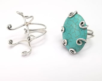 Könnte beinhalten: Zwei silberne Ringe mit einem türkisfarbenen Stein. Der Ring links ist ein schlichtes Band mit einem dekorativen Design. Der Ring rechts hat einen größeren türkisfarbenen Stein mit einem dekorativen Silberdesign darum herum.