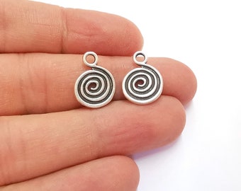 Puede incluir: Dos abalorios de metal plateados con un diseño en espiral. Cada abalorio tiene un bucle en la parte superior para sujetarlo a un collar, pulsera u otra joya.
