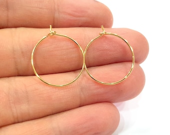 May include: A pair of gold-toned hoop earrings. The hoops are thin and delicate, and they are perfect for everyday wear.