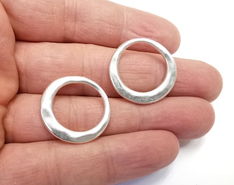 May include: Two silver-toned metal rings with a hammered finish. The rings are round and have a smooth, slightly textured surface.
