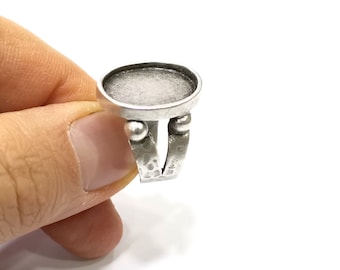 May include: A silver ring with a round, clear glass bezel. The ring has a textured band and two small silver balls on each side of the bezel.