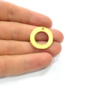 May include: A gold-colored metal circle with a hole in the center. The circle is about 1 inch in diameter.