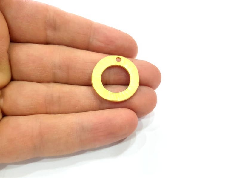 May include: A gold-colored metal circle with a hole in the center. The circle is about 1 inch in diameter.