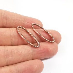 May include: Two copper oval-shaped rings with a textured surface. The rings are approximately 1 inch in diameter.