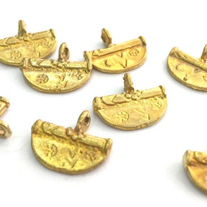 May include: A group of eight gold-toned metal charms with intricate designs. The charms are shaped like half circles and have a loop at the top for attaching to a necklace or bracelet.