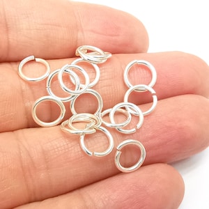 Peut inclure: Gros plan sur un tas de anneaux de saut argentés. Les anneaux sont petits et ronds, et ils sont parfaits pour la fabrication de bijoux.